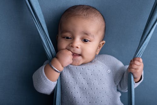 A baby is sitting on a swing and smiling