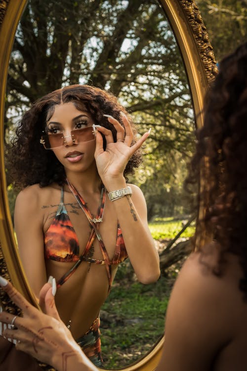 Young Woman in a Bikini Posing in Front of a Mirror in a Park 