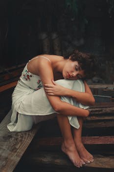 一位身着白色花裙的娴静女子沉思而坐，传递着平静与美丽