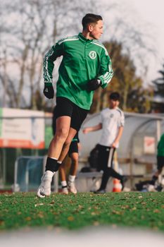 A young soccer player in green sportswear practicing on an outdoor field in Berlin.