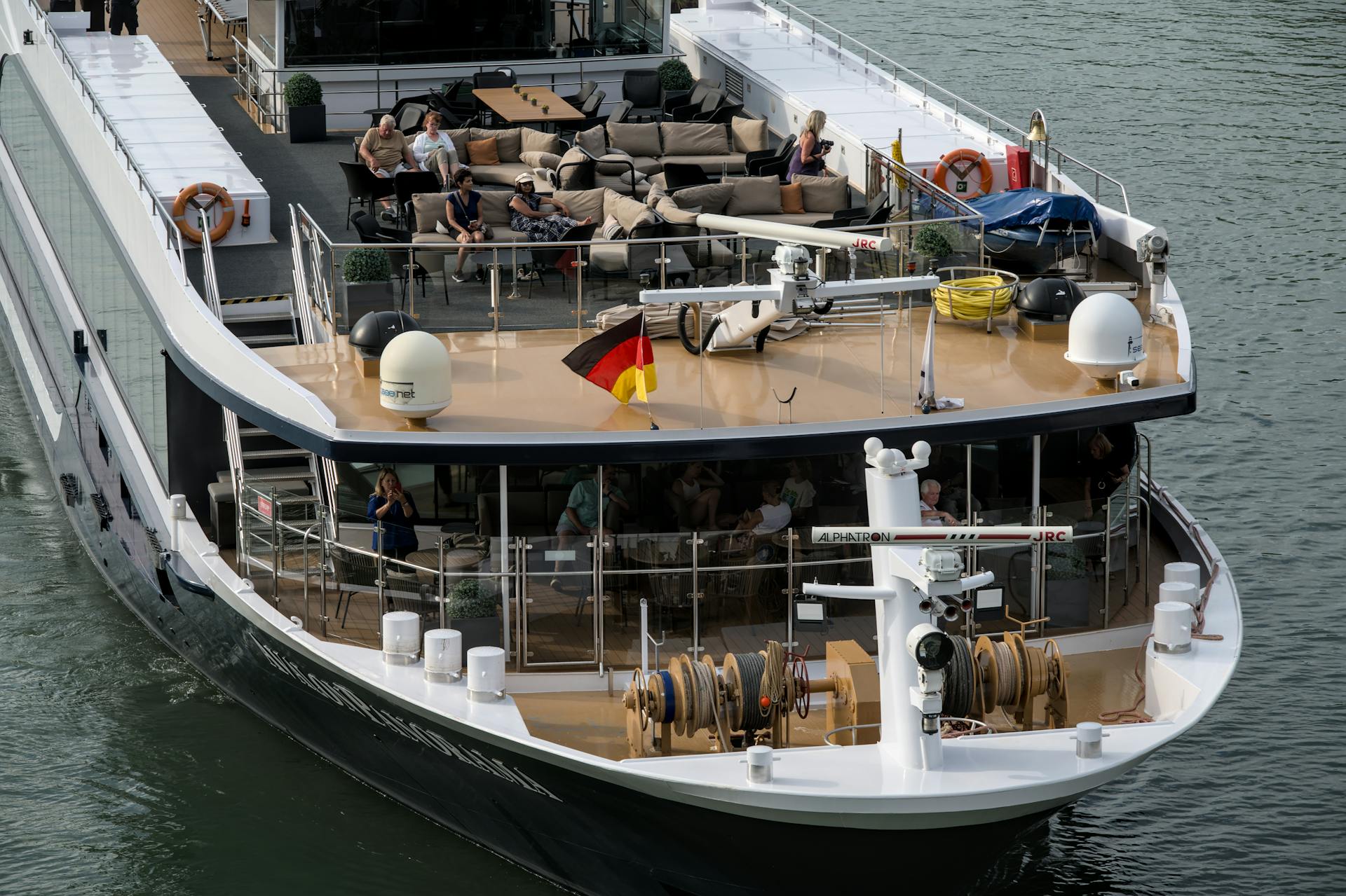 Elegant cruise ship loaded with passengers enjoying scenic views from the top deck.