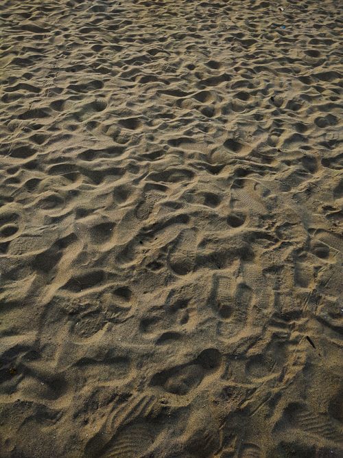 Free Close-up of sandy beach with numerous footprints, showing intricate patterns under sunlight. Stock Photo