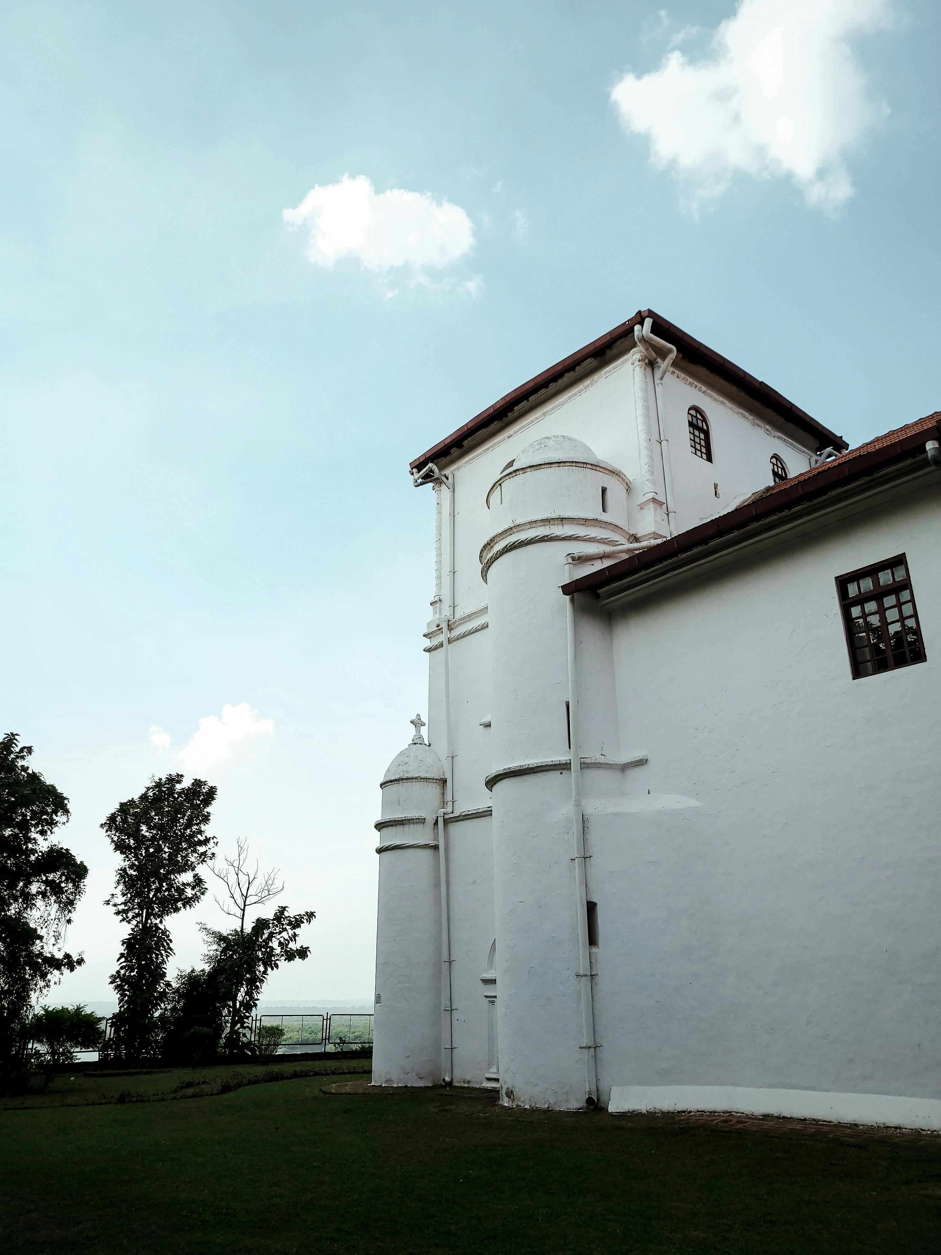 Tall white church with historic architecture in Old Goa, India, under blue skies.