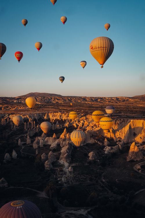 Free Captivating sunrise view of hot air balloons floating over Cappadocia's unique landscape. Stock Photo