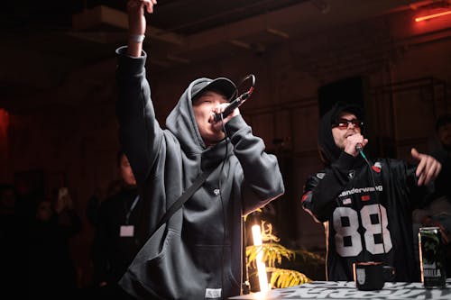 Two men in hoodies singing at a party