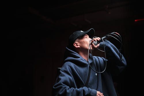 Singer in Cap and Hoodie Holding Microphone