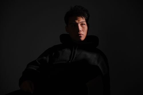 Free A dramatic portrait of a man in a dark sweatshirt with shadows casting on his face. Stock Photo