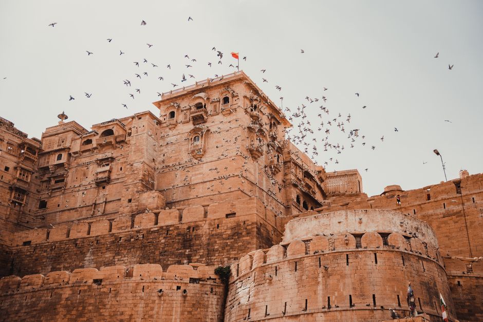 A stunning view of Jaisalmer Fort with birds soaring in the clear sky, epitomizing architectural grandeur.