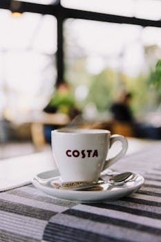 A steaming Costa coffee cup placed on a table inside a trendy café, perfect for lifestyle concepts.