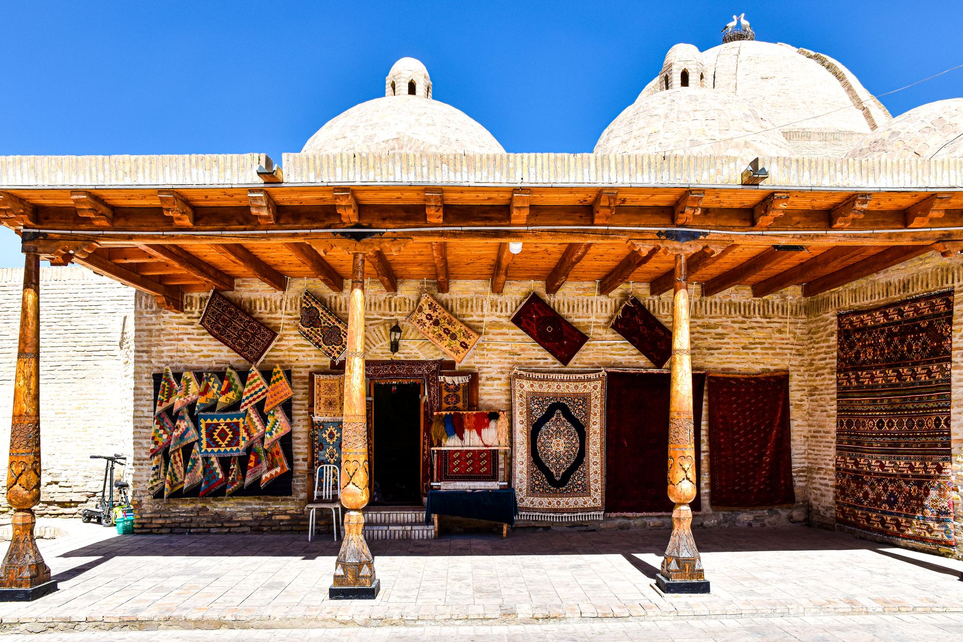 Colorful handmade carpets displayed outside a traditional building in Uzbekistan.