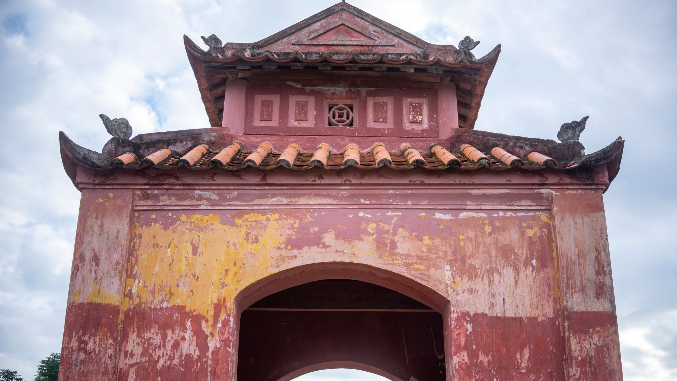 Close-up of an ancient Vietnamese gate showcasing traditional architectural features and a weathered facade.