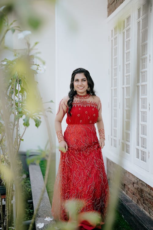 Smiling Bride in an Embroidered Red Wedding Dress Near the House