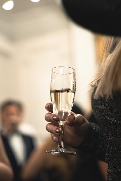 Close-up of a Woman Holding a Glass of Champagne at a Party 