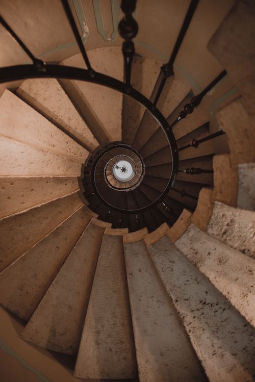 Free Explore the intricate design of a spiral staircase with wrought iron railing in a classic architectural setting. Stock Photo