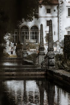 View of Vizcaya Museum's beautiful facade and lush gardens with reflective ponds.