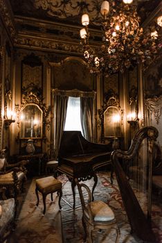 Opulent Baroque room featuring ornate decor, a grand piano, and chandelier lighting.