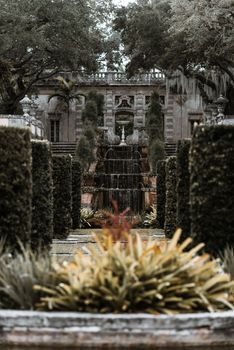 A classic fountain amidst manicured greenery with elegant architectural backdrop.