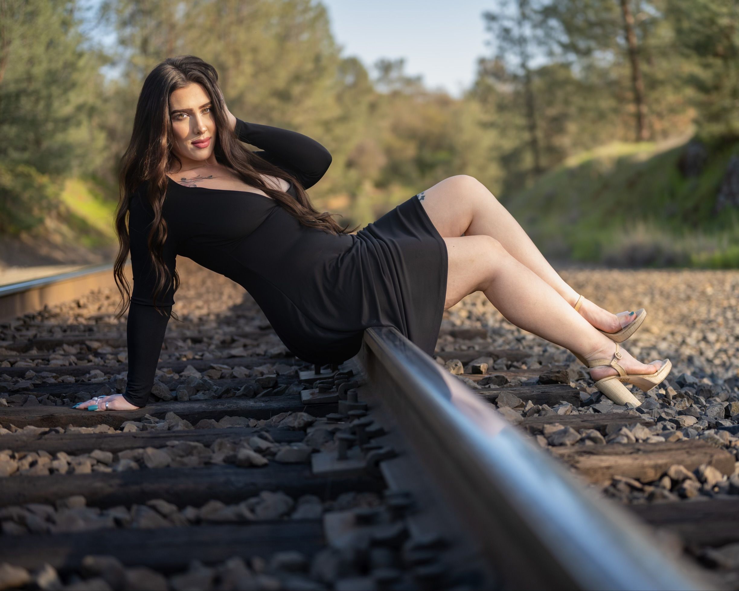 Brunette Woman in Black Dress Posing on Railway Tracks  Free Stock Photo