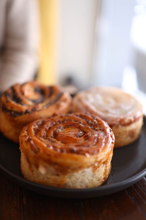 Free Close-up of freshly baked cinnamon rolls glazed with sugar on a dark plate. Stock Photo
