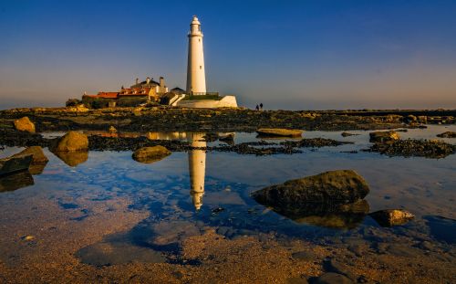 Free Stunning landscape of St. Mary's Lighthouse reflecting in the sea during sunset. Stock Photo