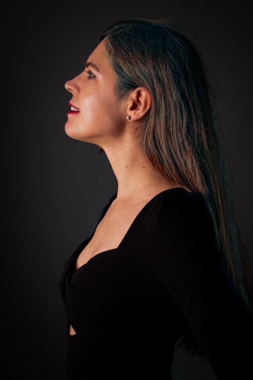Free Profile portrait of a smiling woman with elegant attire in a studio setting, showcasing glamour and sophistication. Stock Photo