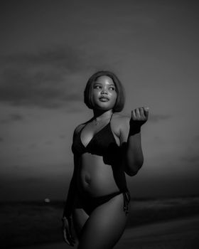 A black and white portrait of a confident woman in a bikini posing on a beach, showcasing beauty and elegance.