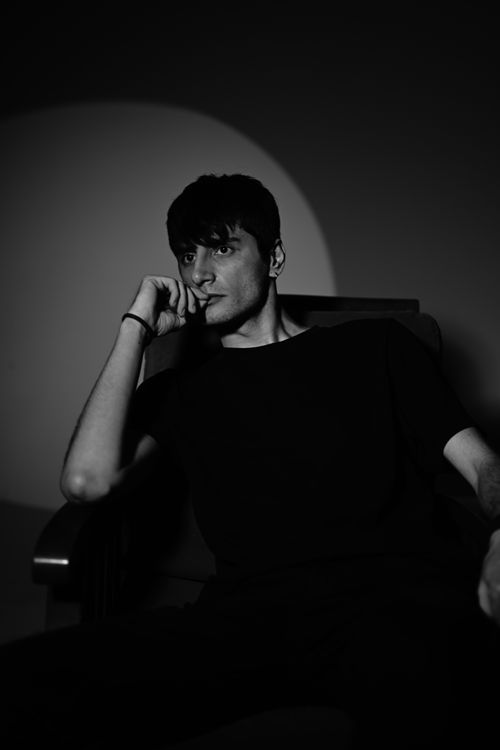 Free A contemplative black-and-white portrait of a man sitting pensively in shadowed lighting. Stock Photo