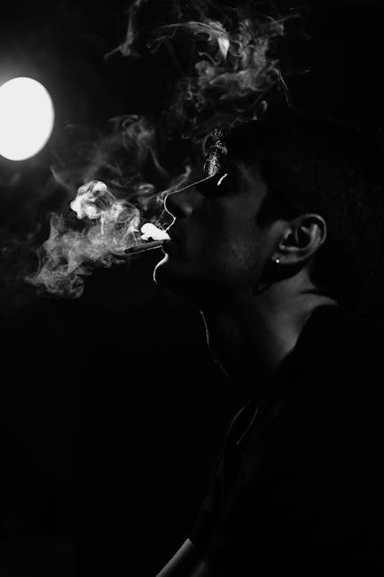 Silhouette of a man exhaling smoke in dramatic black and white with strong contrasts.