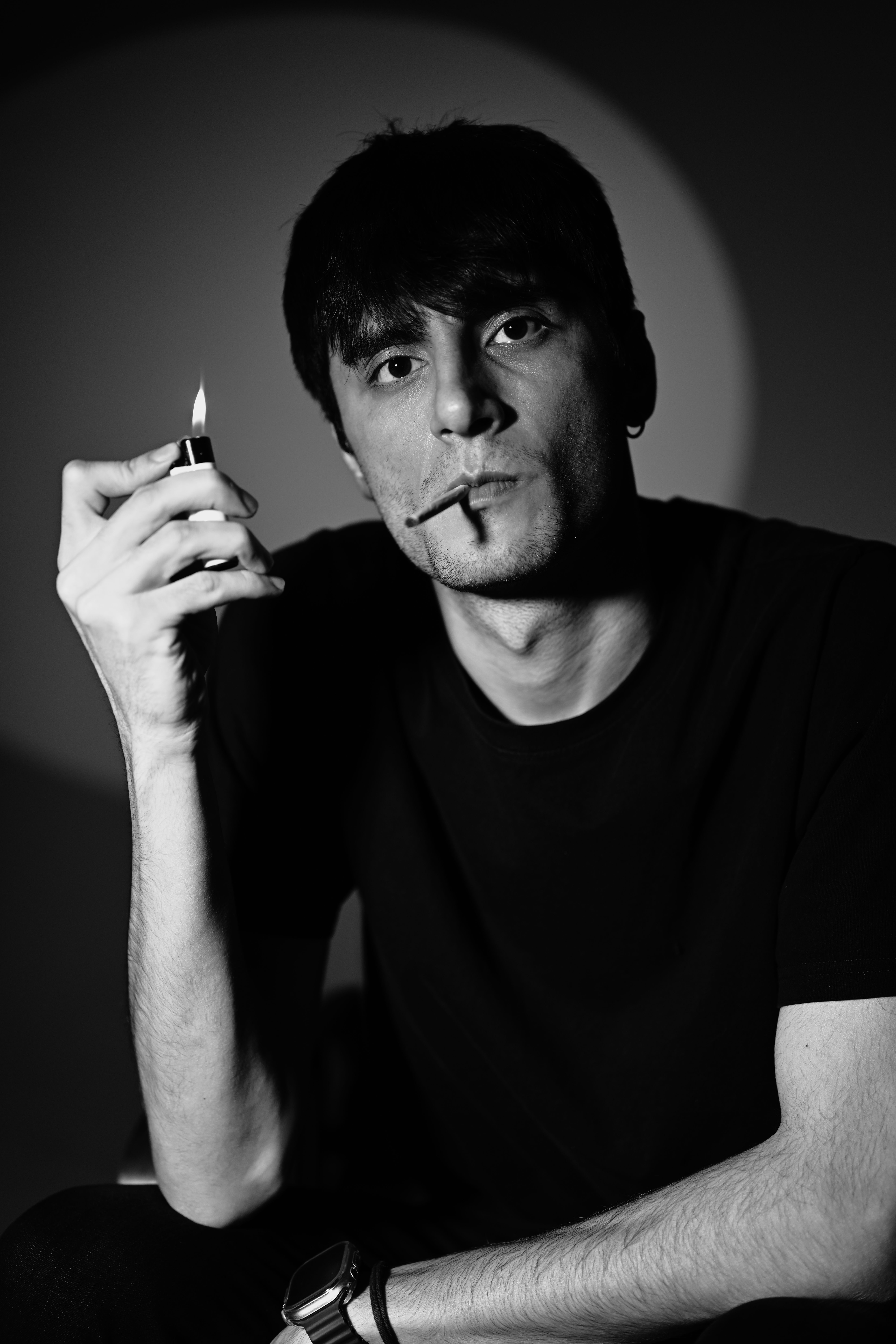 Stylish black and white portrait of a man with lighter and cigarette, conveying a moody and intense look.