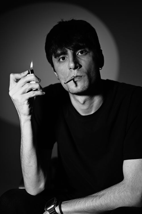 Free Stylish black and white portrait of a man with lighter and cigarette, conveying a moody and intense look. Stock Photo
