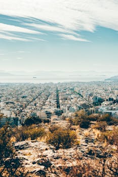 Scenic aerial view of an urban landscape with mountains in the distance under a clear sky.
