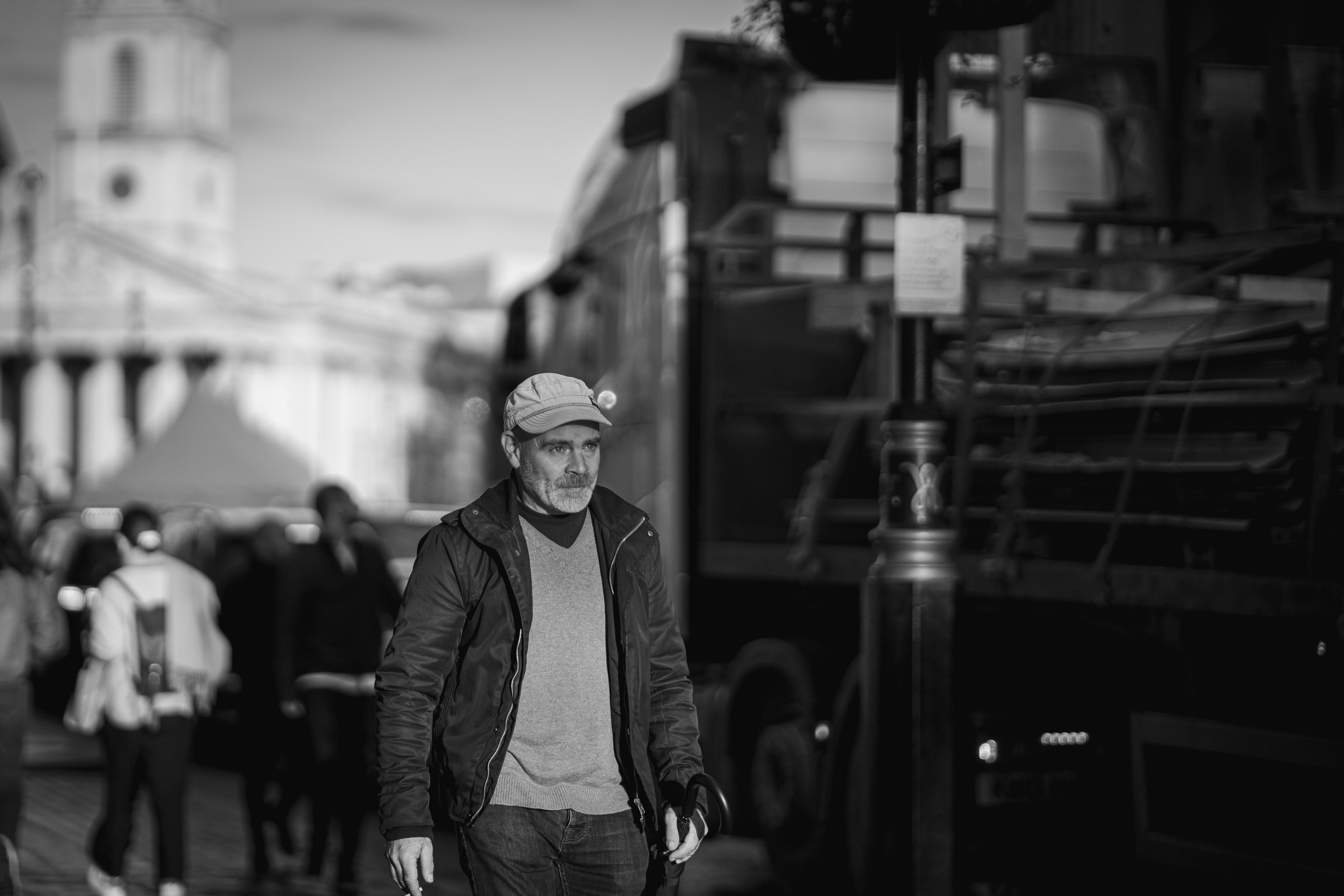 A man walks through a bustling city setting in monochromatic tones, adding a dramatic urban feel.