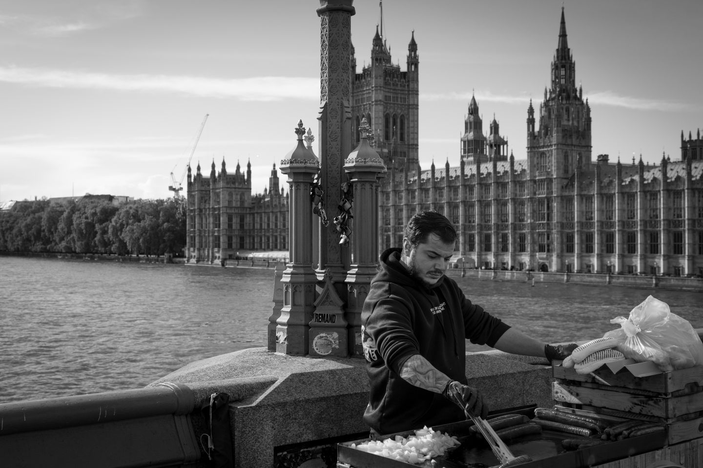 A street vendor prepares food on Westminster Bridge with the Houses of Parliament in the background.