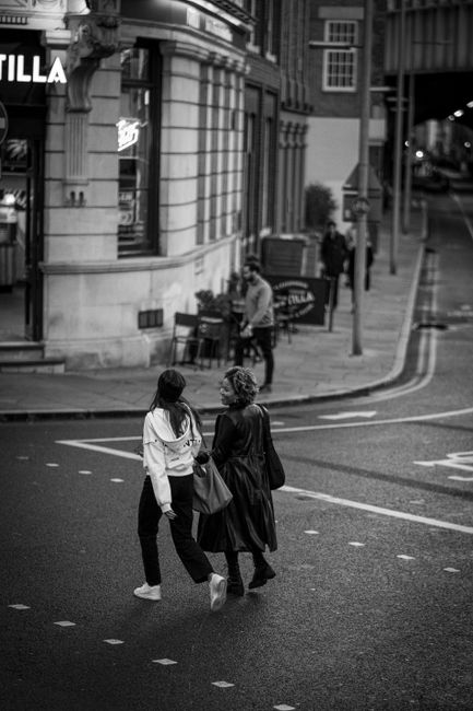 Monochrome street scene of two women crossing a city street in downtown.