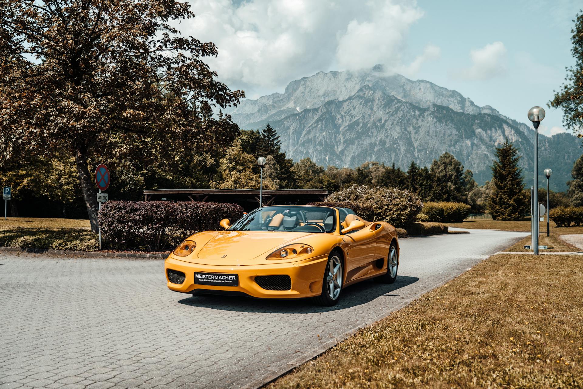 Luxury yellow sports car on a paved road with mountain backdrop, ideal for transportation themes.