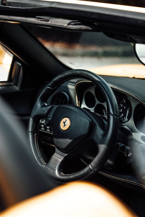 Free Close-up of a luxury car's leather steering wheel with brushed metal accents, showcasing elegance and design. Stock Photo