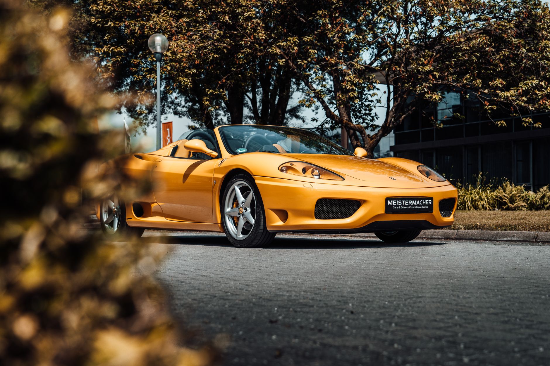 A striking yellow convertible car parked on a scenic city street during autumn.