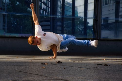Free A breakdancer executes a handstand on a Berlin sidewalk, showcasing urban street performance. Stock Photo