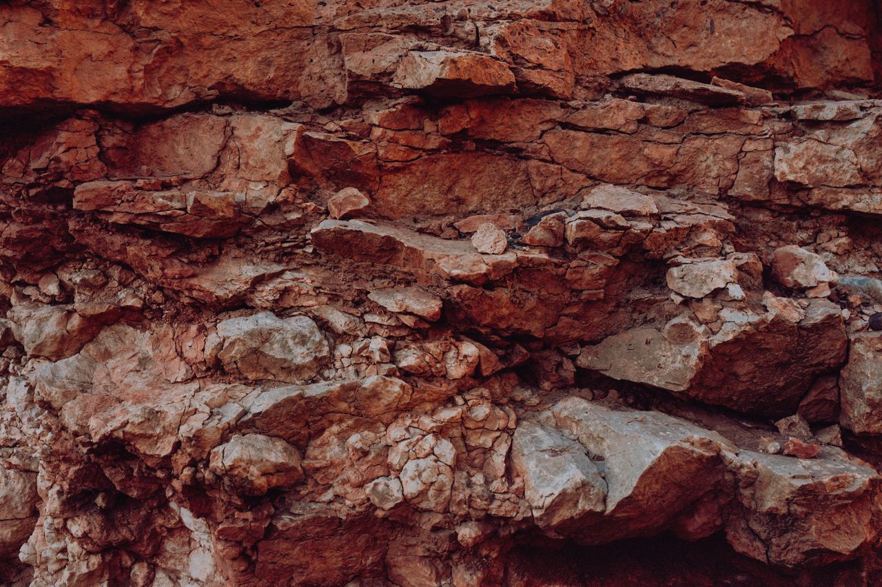 close up of weathered and textured red rock cliff showcasing natural e