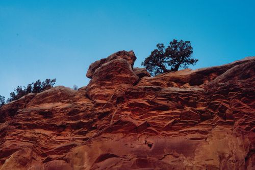 Free A captivating red rock formation with sparse trees set against a clear blue sky. Stock Photo