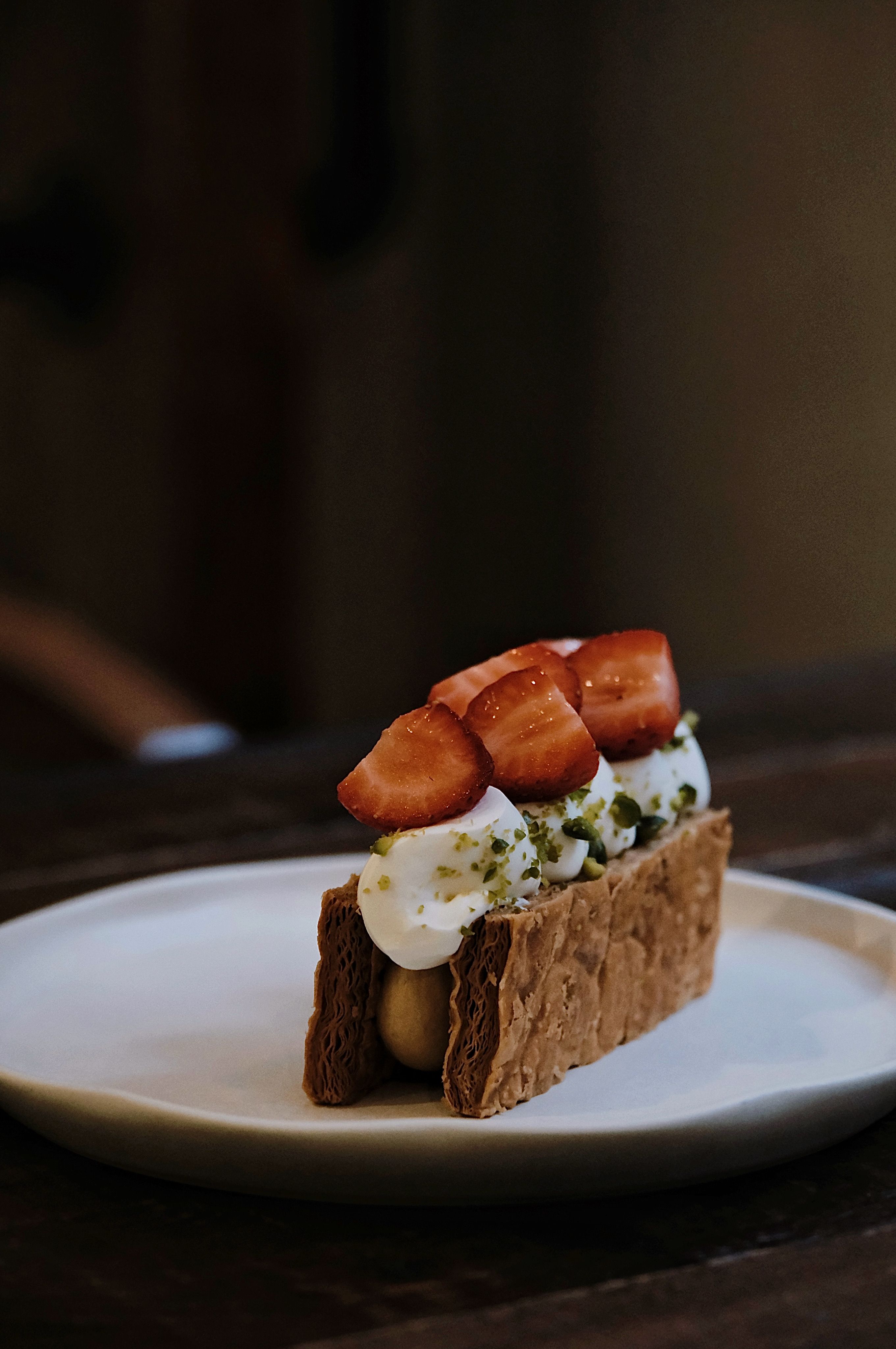A sliced mille-feuille showing three crisp golden pastry layers separated by thick vanilla pastry cream, topped with white glaze feathered with chocolate lines.