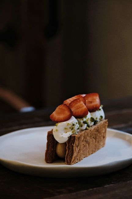 A sliced mille-feuille showing three crisp golden pastry layers separated by thick vanilla pastry cream, topped with white glaze feathered with chocolate lines.