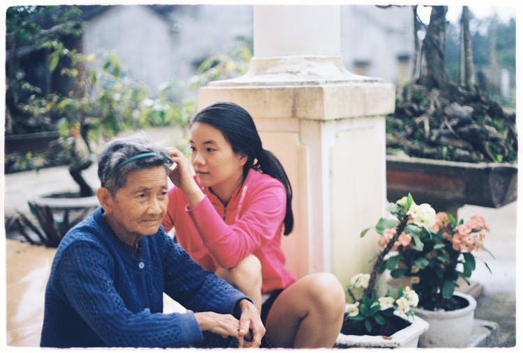 A Young Girl And Elderly Woman Sitting On A Patio 