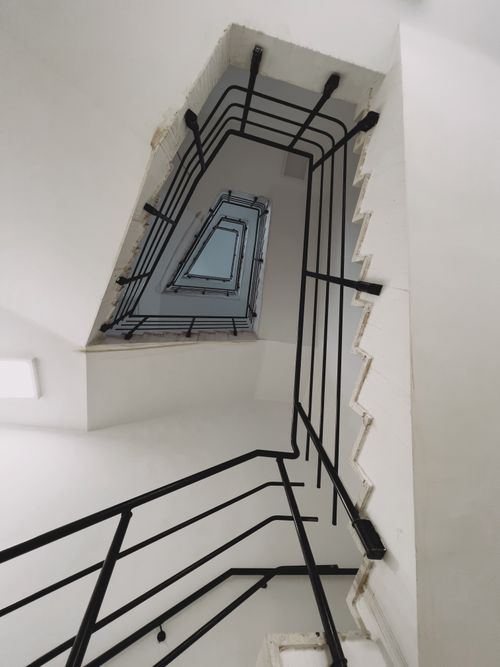 Free Dramatic black and white view of a staircase with railing in a modern building. Stock Photo