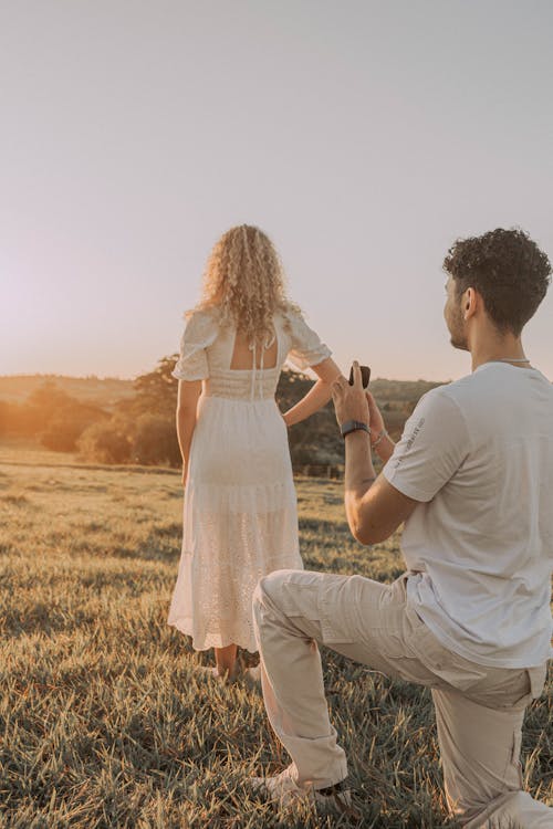 Man Kneeling behind Woman in White Dress at Sunset