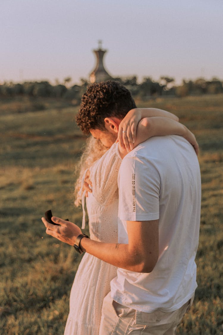 A Couple Hugging And Man Holding An Engagement Ring 