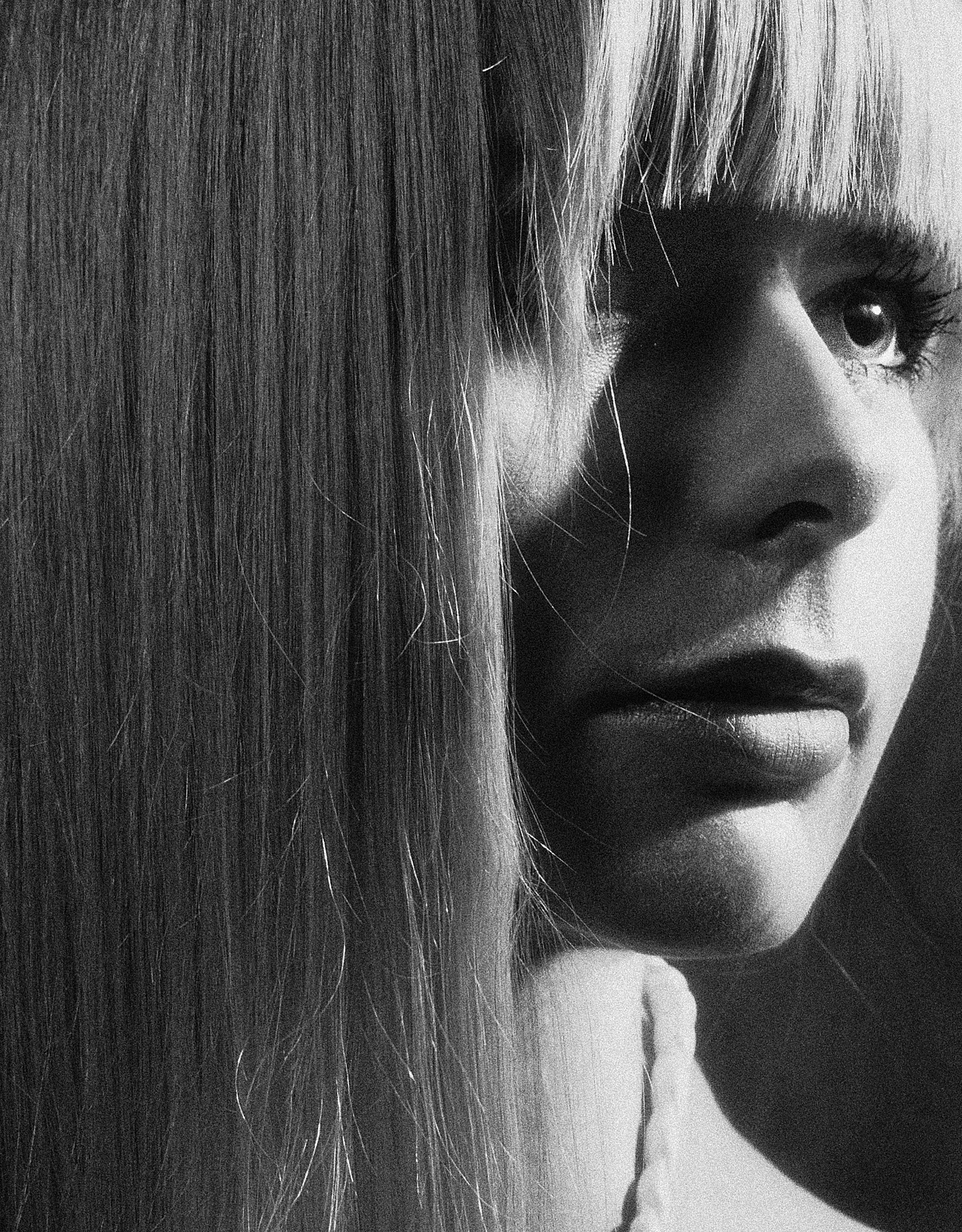 Dramatic black and white portrait of a woman with long blonde bangs