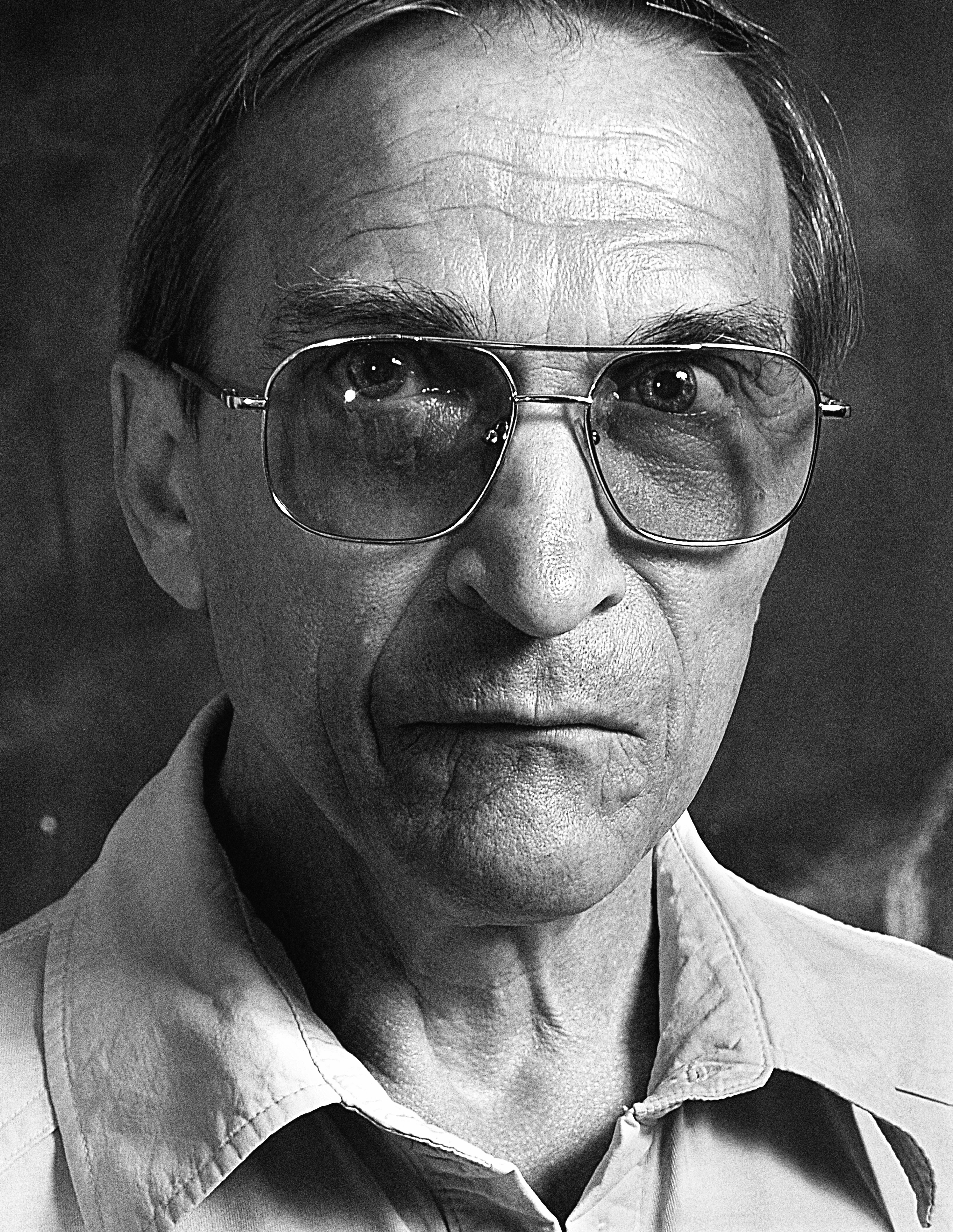 Black and white portrait of an elderly man wearing glasses, showcasing wisdom and experience.