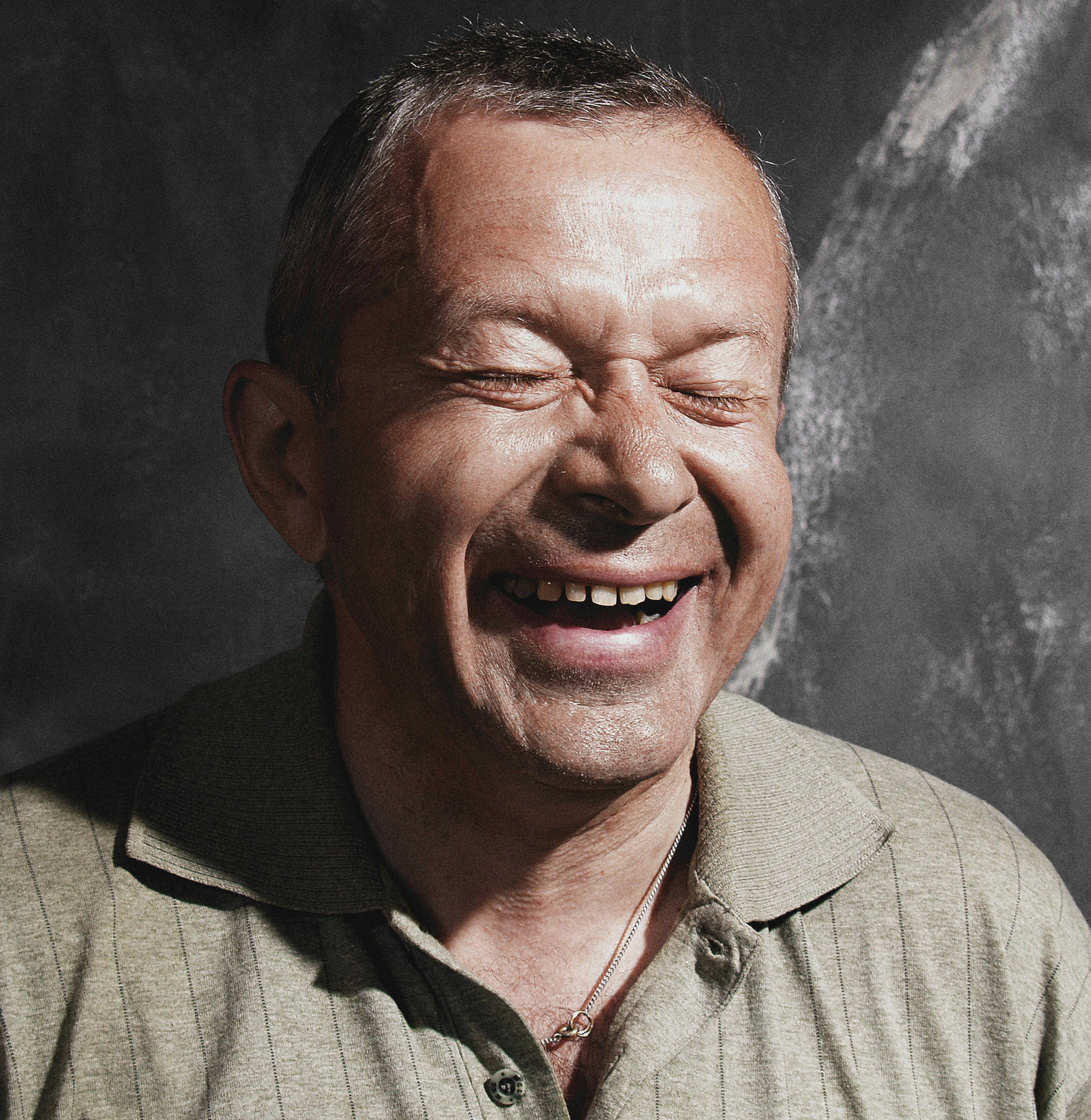 A cheerful man with eyes closed and a big laugh, expressing pure joy.