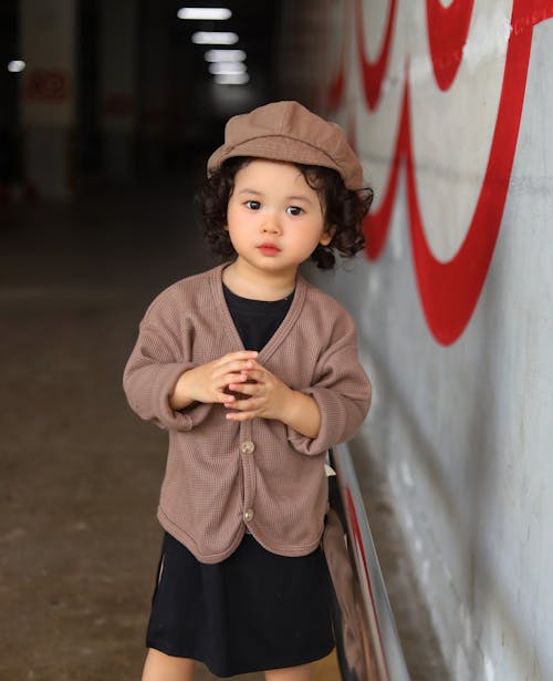 Girl in Hat Standing by Wall